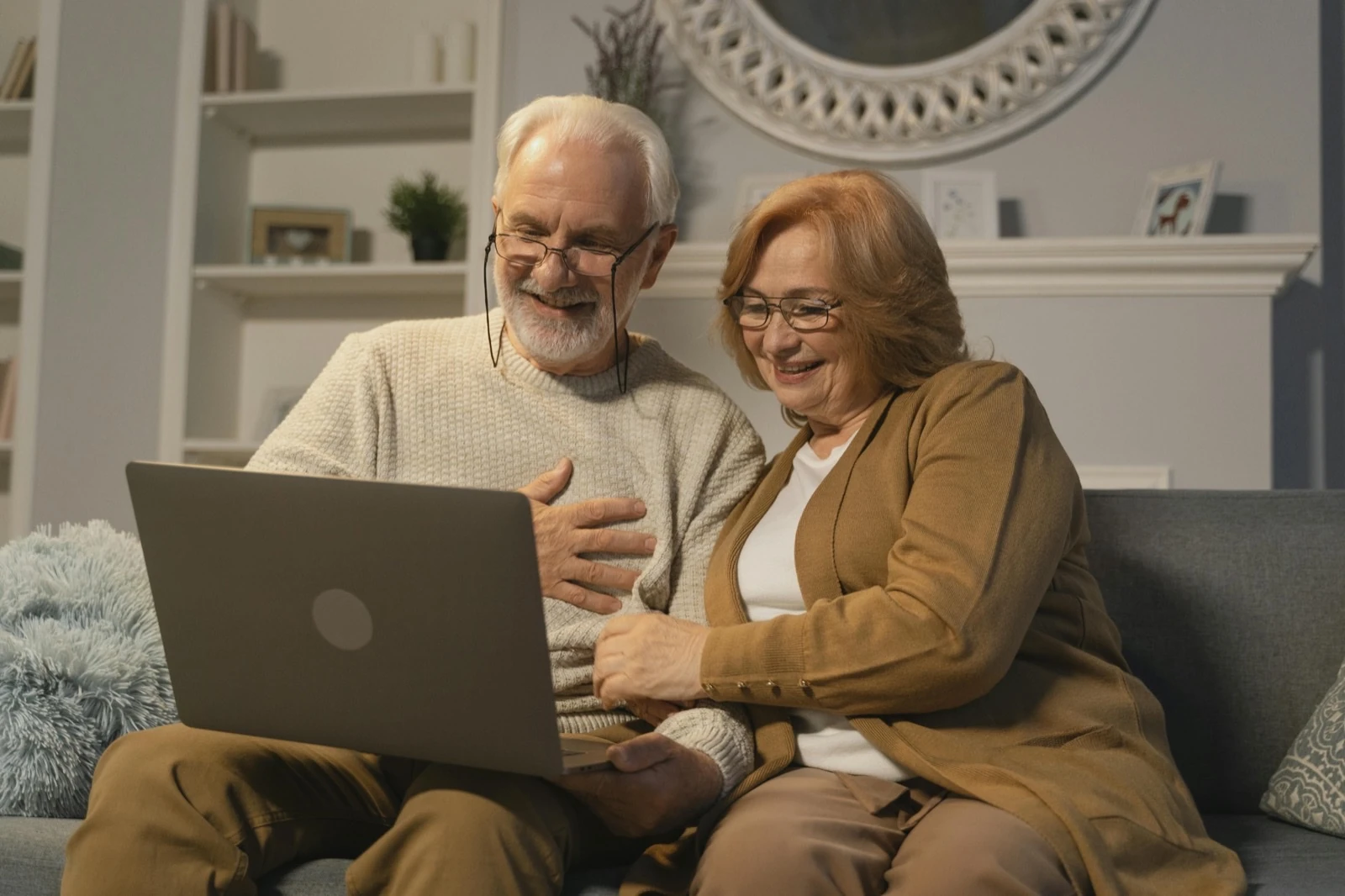 Older couple using a laptop together on a sofa