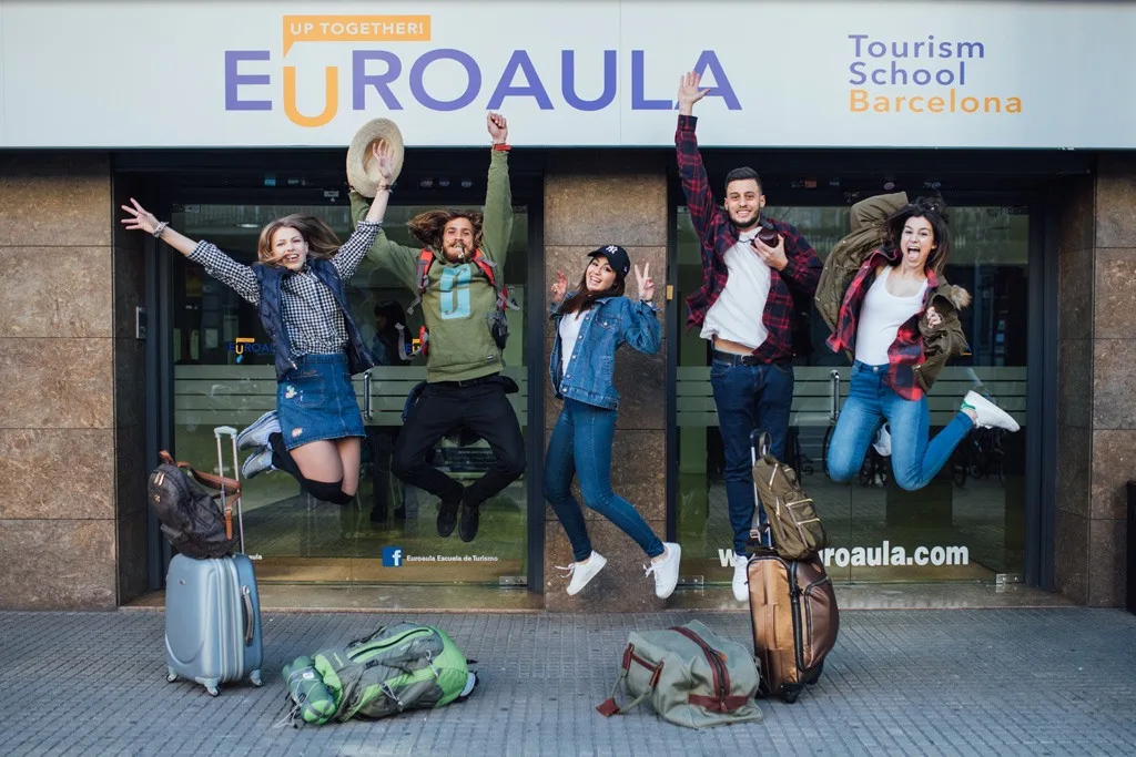 Euroaula Tourism School Barcelona — students jumping at the campus entrance with luggage