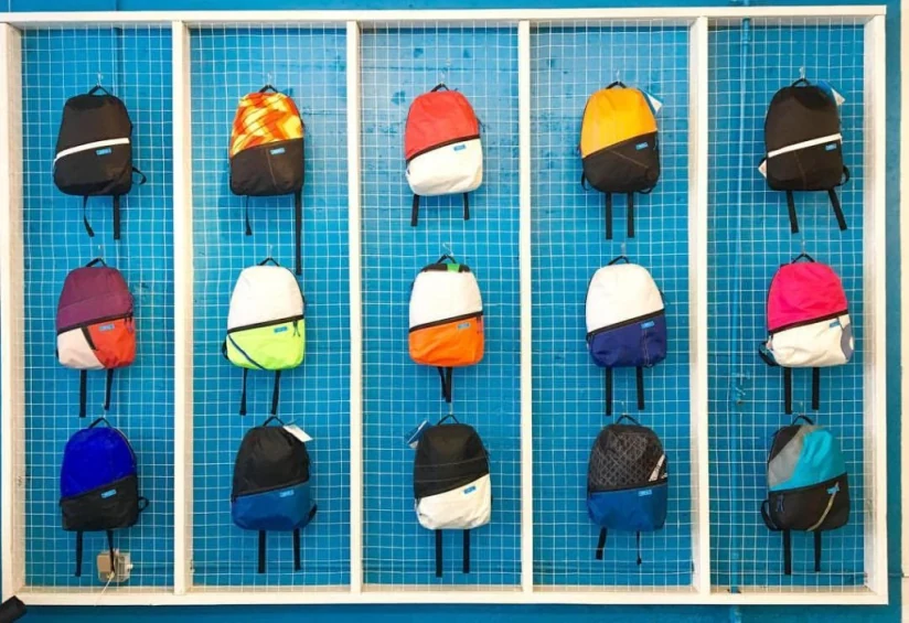 Colorful Mafia recycled-sail backpacks on a blue display wall
